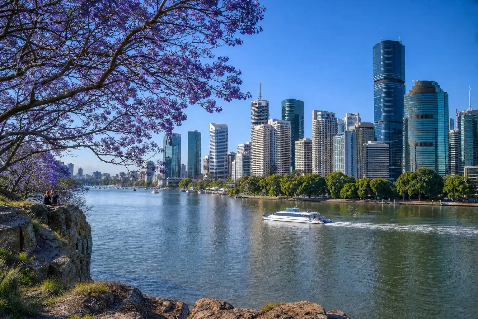 The Brisbane River and the city towers from the Kangaroo Point cliffs on a spring morning, jacarandas in flower and a ferry crossing
